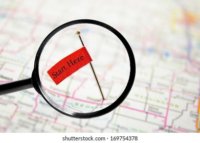 Pin With Stuck Into A Map With Magnifying Glass And Start Here Text