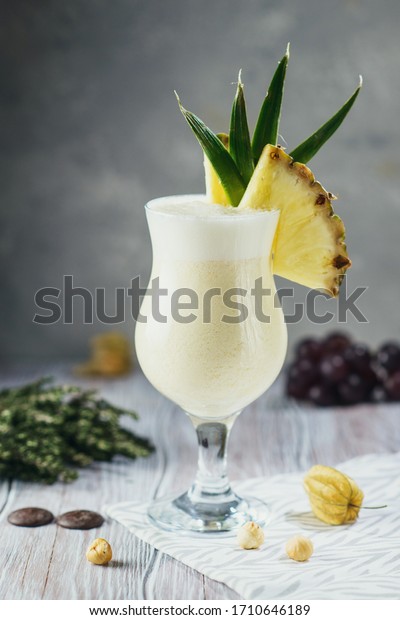 Pina Colada cocktail with\
decorations on craft light background with berries, nuts and\
greens