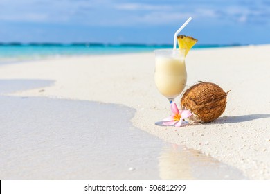 Pina Colada cocktail on the beach with coconut and exotic flower