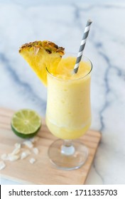 Pina Colada Cocktail on Marble Counter with Pineapple Slice to Garnish and Lime and Coconut on Board Slush Drink 