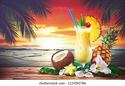 Pina colada fresh cocktail drink served with pineapple and coconut on the beach at sunset
