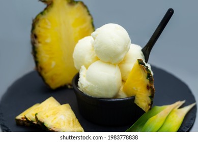 Pine apple ice cream in the black bowl on the table, tropical fruit, leaves. High quality photo - Powered by Shutterstock