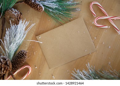 Pine Boughs, Candy Canes & Envelope On A Cutting Board (flat Lay Image)