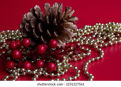 Pine Cone, red berries, gold chain, red background - Shutterstock ID 2231227561