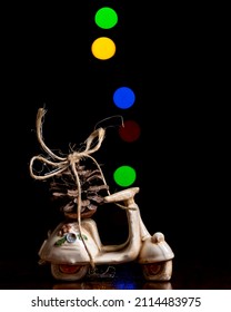A pine cone tied with string to a model scooter with colored lights with bokeh effect in the background