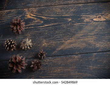 Pine cones in the corner, located on the old dark brown table. Place for an inscription. Nice background.