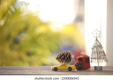 pine cones on miniature car and Christmas tree decorations on wooden table with nature outdoor view - Powered by Shutterstock