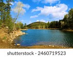 Pine and deciduous trees surrounding an alpine lake taken at Goldwater Lake in Prescott, AZ