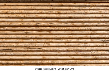 Pine log wall. The texture of the facade is made of real wooden logs. Natural wood background.