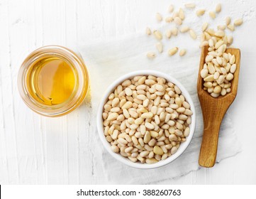 Pine Nut Oil And Bowl Of Pine Nuts On White Wooden Background. Top View