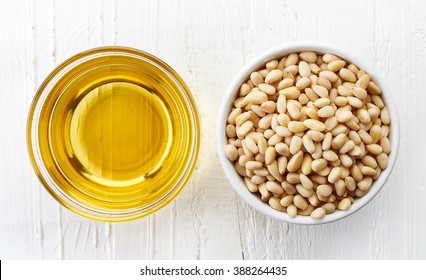 Pine Nut Oil And Bowl Of Pine Nuts On White Wooden Background. Top View