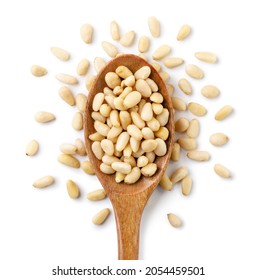 Pine nut in a wooden spoon and scattered close-up on a white background. Top view
