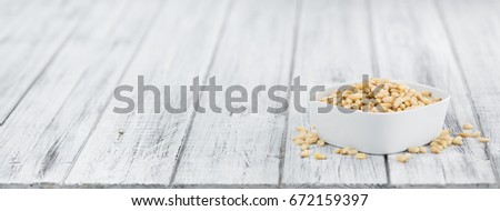 Pine Nuts on rustic wooden background (close-up shot)