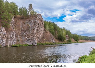 Pine trees and rocks on the river shore with fall foliage around. Rocky shore of a mountain river. Sunny scenery for trekking and adventure on outdoors. - Powered by Shutterstock