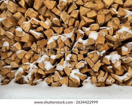 Pine wood cut and split into pieces stored in a pile with a small amount of snow, as winter firewood. Close-up as background.