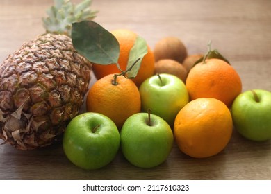Pineapple, apples, oranges, lemons and kiwis on a wooden table. Selective focus.  