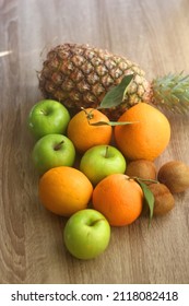 Pineapple, apples, oranges, lemons and kiwis on a wooden table. Selective focus.