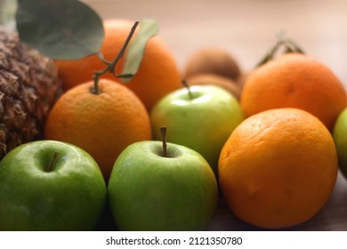 Pineapple, apples, oranges, lemons and kiwis on a wooden table. Selective focus.