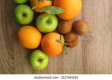 Pineapple, apples, oranges, lemons and kiwis on a wooden table. Top view.