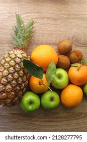 Pineapple, apples, oranges, lemons and kiwis on a wooden table. Top view.