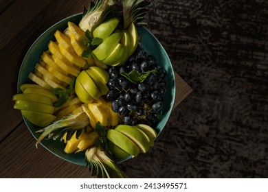 Pineapple, apples and red grapes cut into pieces lie in a deep ceramic bowl. Stand the piala on a wooden table. - Powered by Shutterstock