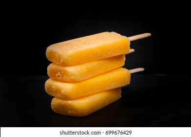 Pineapple, Apricot and Mango Popsicles on black background. Selective focus.