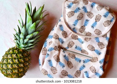 Pineapple and backpack on the table. Summer flat lay.