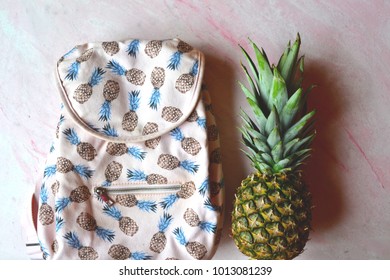 Pineapple and backpack on the table. Summer flat lay.