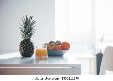 Pineapple, bananas, oranges and glass with fresh juice on the table. - Shutterstock ID 1358211890