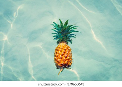 Pineapple into water on sunny beach - Powered by Shutterstock