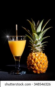 a pineapple juice with fruit on black background