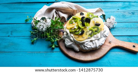 Pineapple and kiwifruit Australian Pavlova on rustic blue background. Selective Focus