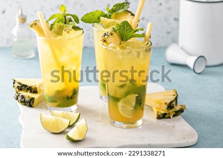 Pineapple mojito with limes and mint and a slice of pineapple garnished with a sugar cane stick