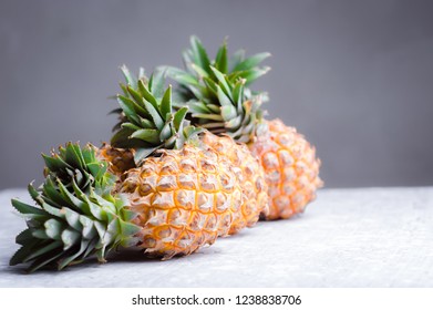 Pineapple on empty white cement table over gray cement wall background