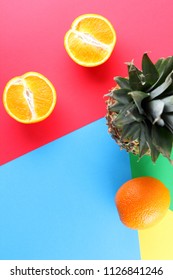 Pineapple and oranges on a multicolored background, tropical fruit top view, pineapple and halves of oranges in pop art style, vegetarian food in minimalism style, copy space