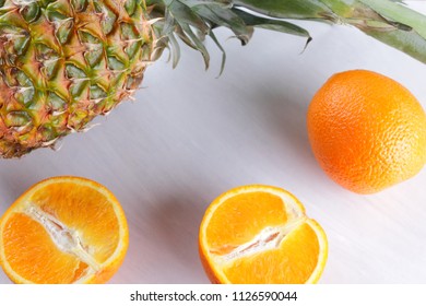 Pineapple and oranges on white background, citrus top view, cut oranges for fruit salad, vegetarian food, tropical fruits for diet, copy space