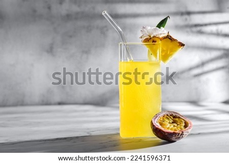 pineapple with passion fruit juice. on a gray background, sunlight, sliced passion fruit and pineapple pieces nearby. Decorated with a flower, food styling 