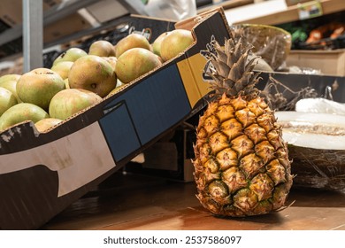 A pineapple sits on a table next to a cardboard box that says 