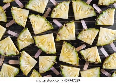 Pineapple slice popsicles on a black rustic wood background