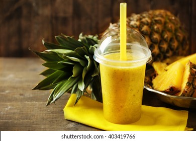 Pineapple Smoothie In Plastic Cup On Wooden Background