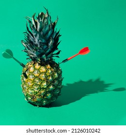 Pineapple stabbed by two dart arrows on green background. Shadow art.