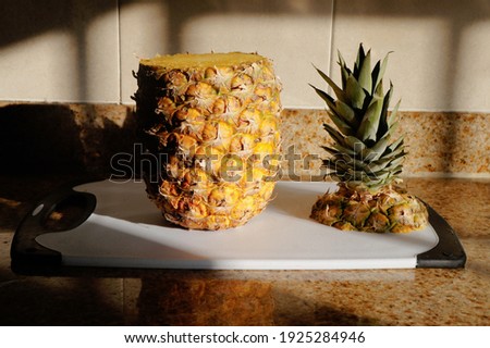 
pineapple with the top cut off, placed on a white table in the kitchen with natural light