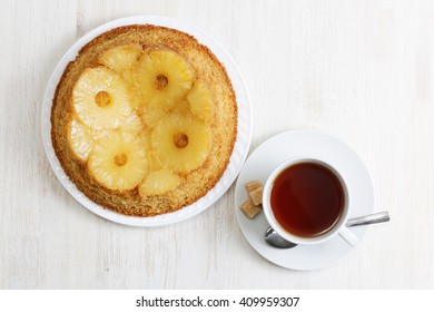 Pineapple Upside Down Cake And Cup Of Tea On White Wooden Table. Top View.