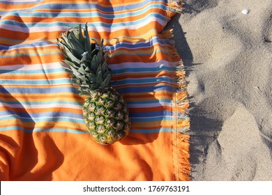 pineapples and coconuts on an orange and colored striped towel