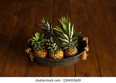 Pineapples In A Metal Basin On A Wooden Background