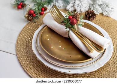 Pinecones festive place setting napkin decoration for dinner; glamorous holiday gold table centerpiece; cutlery on plate with Christmas artificial arrangement - Powered by Shutterstock