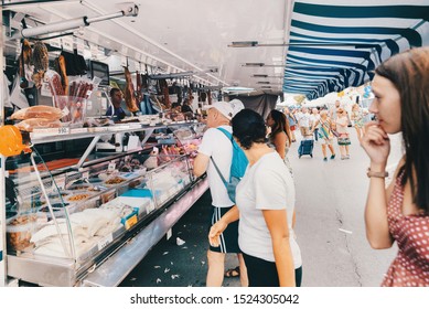 Pineda De Mar, Barcelona, Spain - August, 16, 2019: Sale Of Meat Products - Jamon, Ham And Sausages At A Street Fair. Big Tent And Shoppers