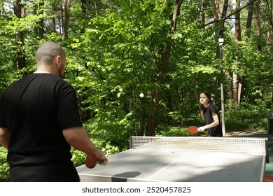 Ping pong players playing table tennis, couple in a match, hobby and fitness on a sunny day. - Powered by Shutterstock