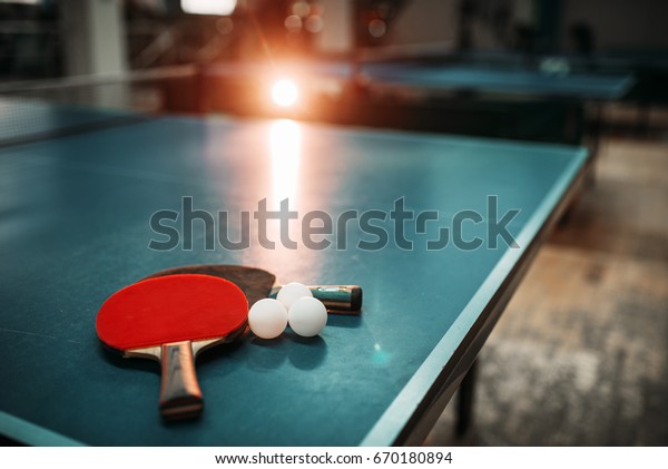 Ping pong\
table, rackets and balls in a sport\
hall