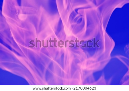 Pink abstract glare of light and flame, colored smoke on a blue background.